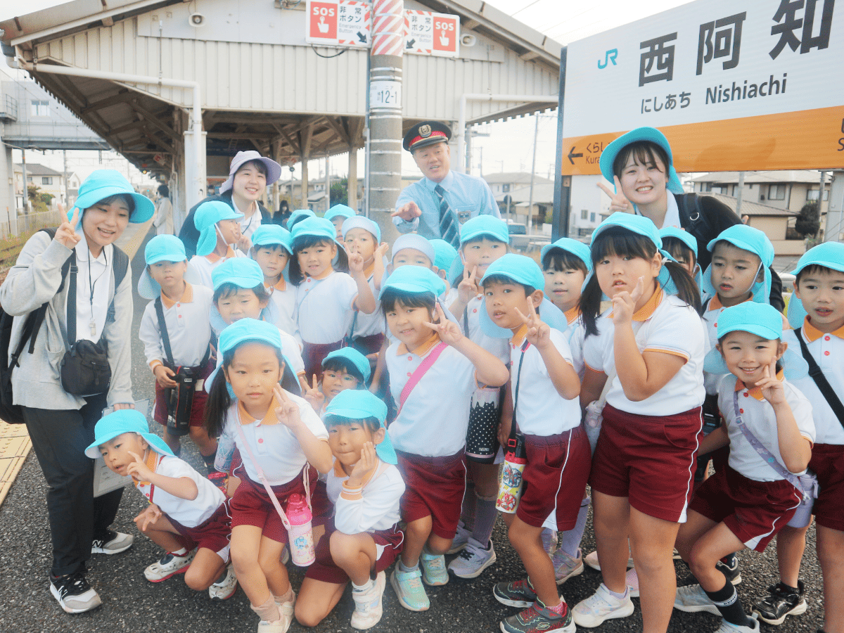 駅で写真を撮る先生と園児たち
