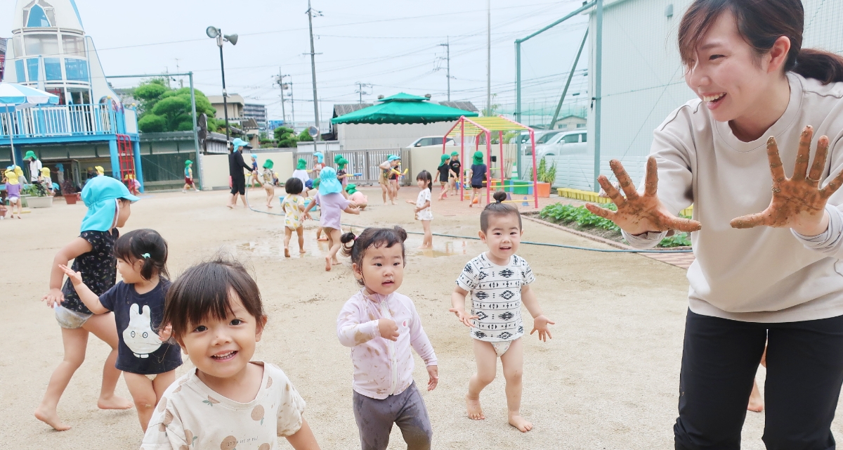 泥遊びをする園児と先生