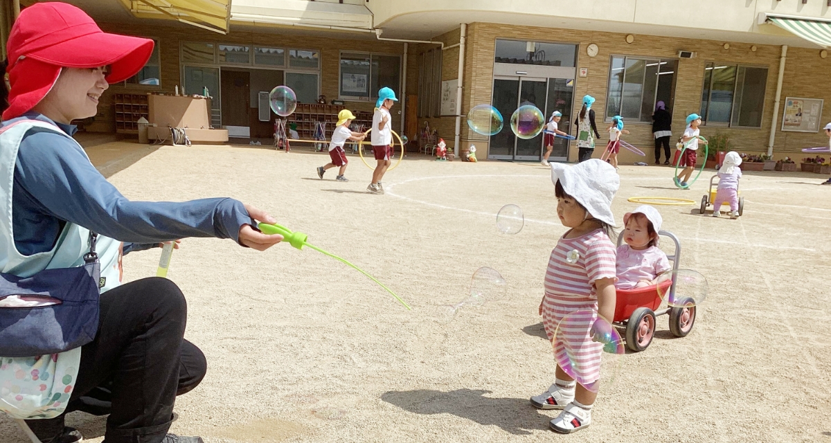 シャボン玉で遊ぶ園児と先生